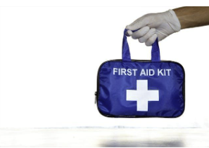 Close-up of a hand holding a first aid kit with a white cross on it.